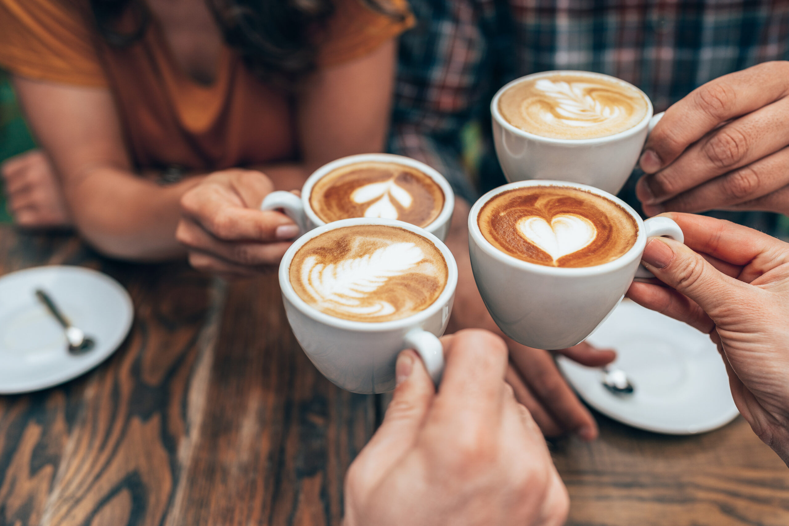 People hands holding cups of cappuccino. Friends drinking coffee together. Hands holding modern looking cups of cappuccino. Tasty and good looking coffee.