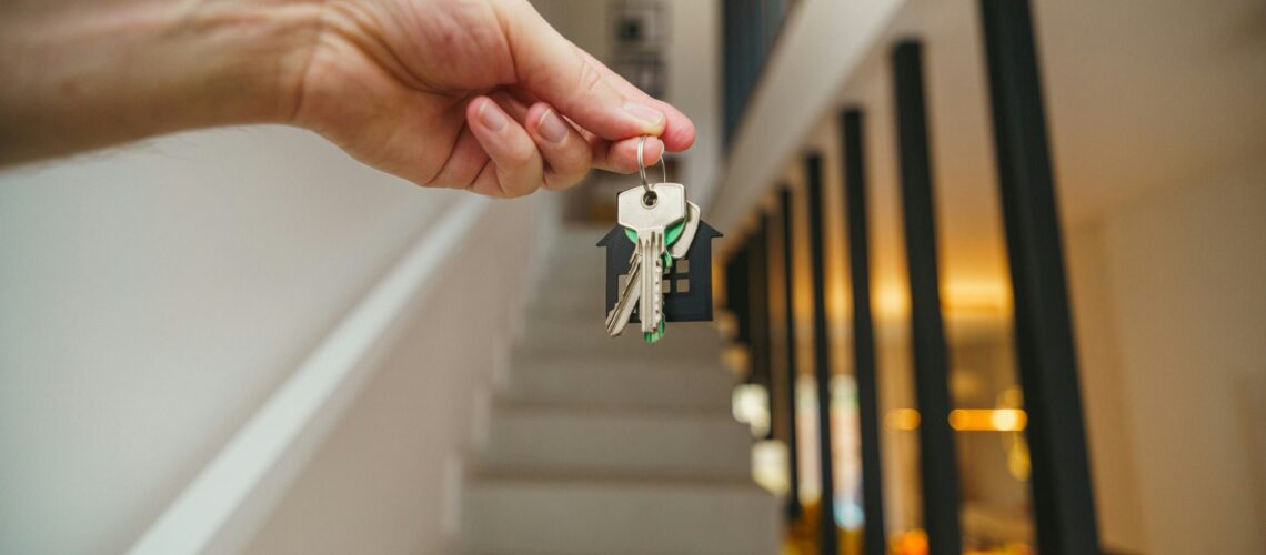 First home buyer holding up keys to a new home in front of stairs