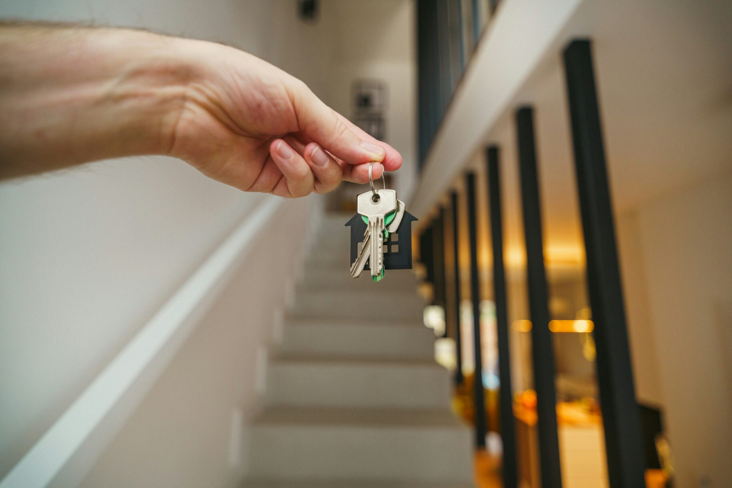 First home buyer holding up keys to a new home in front of stairs